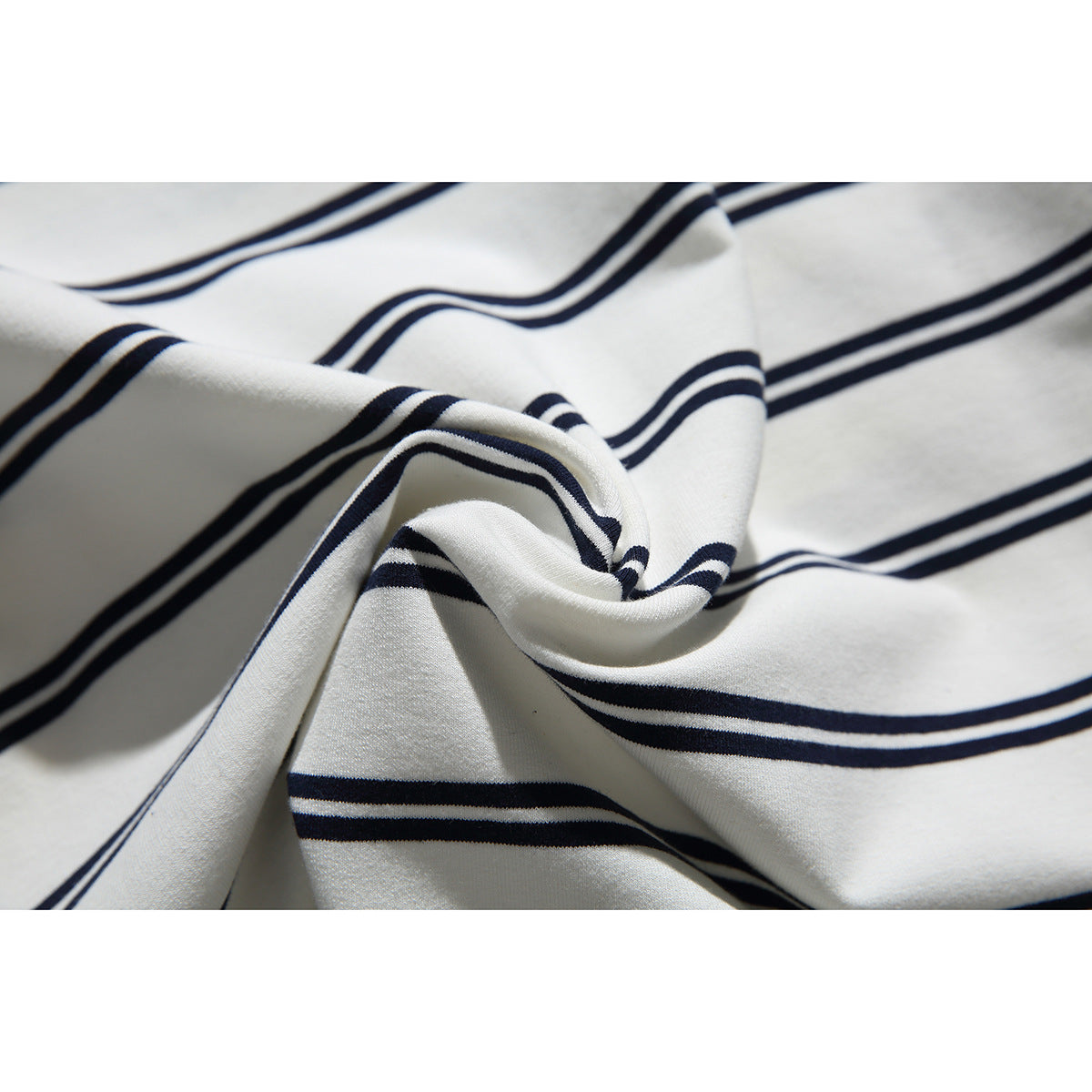Close-up of ivory fabric with navy stripes gathered into folds.