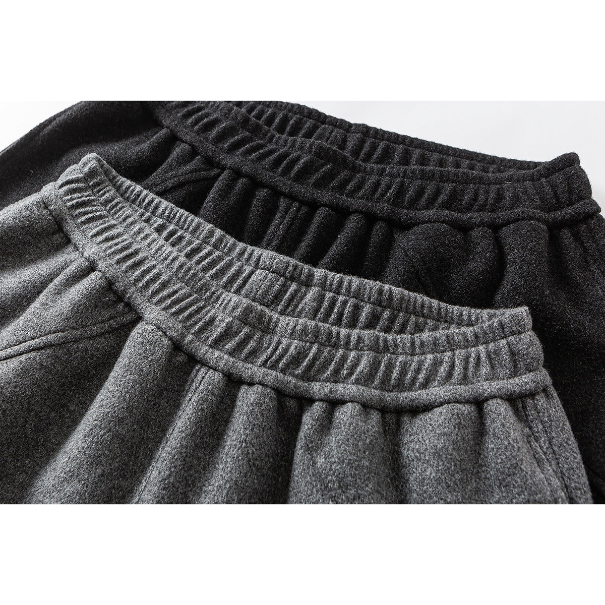 Close-up of gray and black pants showing their gathered elastic waistbands and textured fabric.