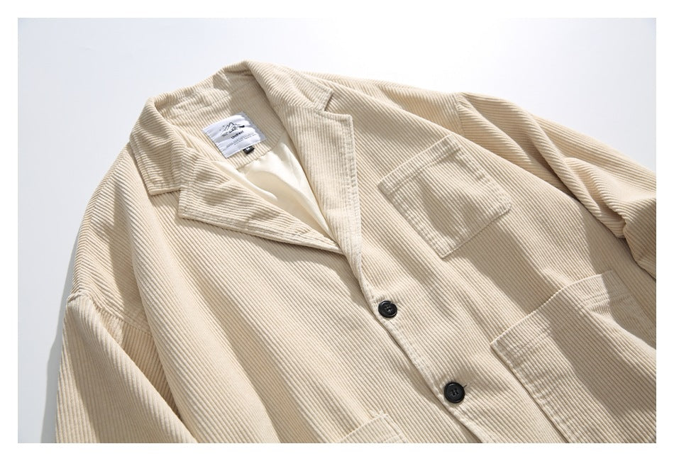 Close-up of a cream corduroy jacket front, showing notched lapels, dark buttons and patch pockets.