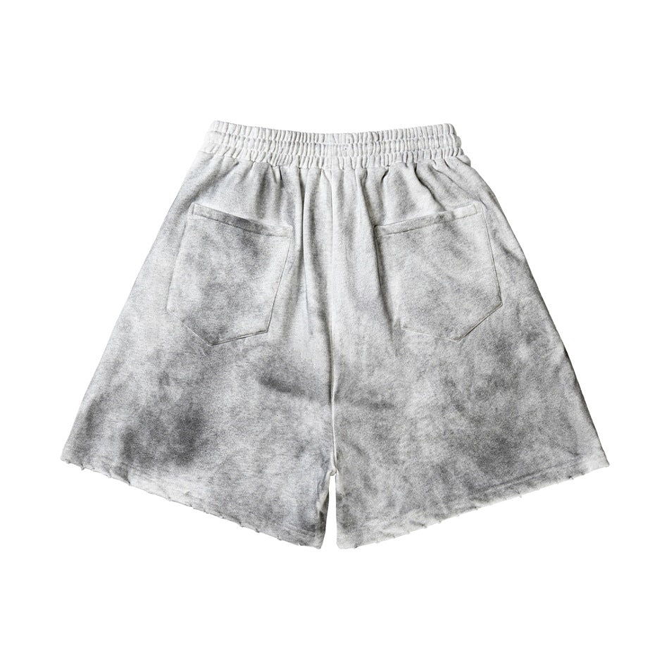 Back view of gray athletic shorts with an elastic waistband, two patch pockets, and distressed hems.