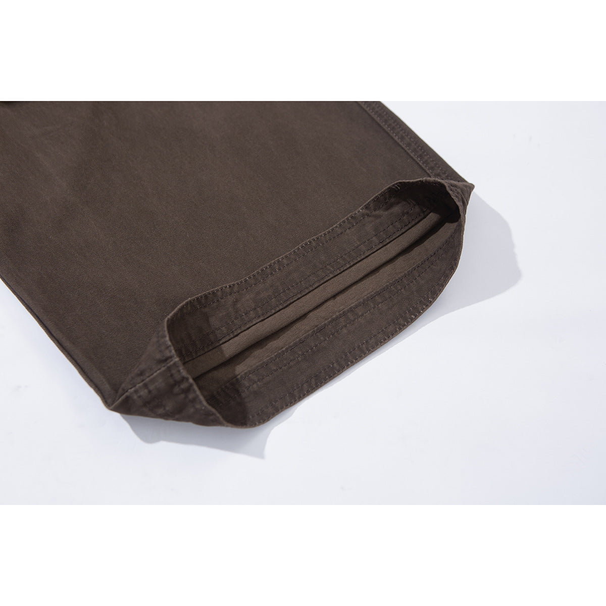 Close-up of the hem of dark brown pants, showing the folded edge and rows of stitching.