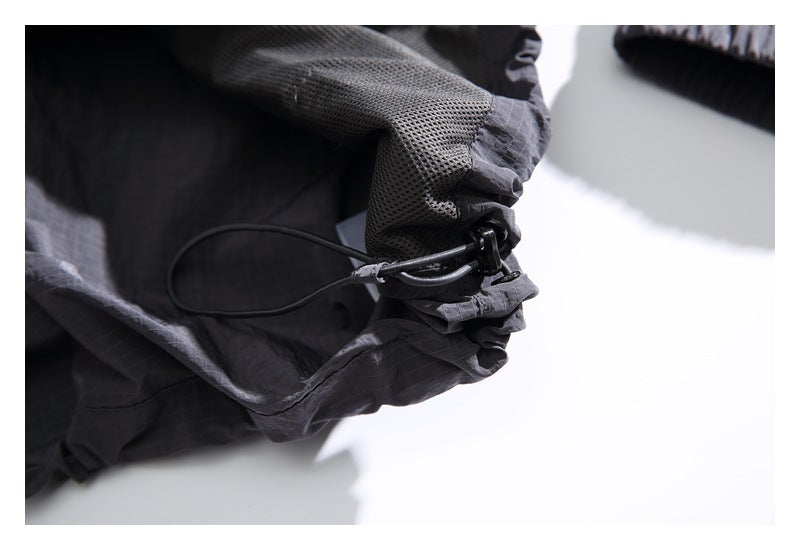 Close-up of a jacket edge with mesh lining and an adjustable elastic cord toggle.