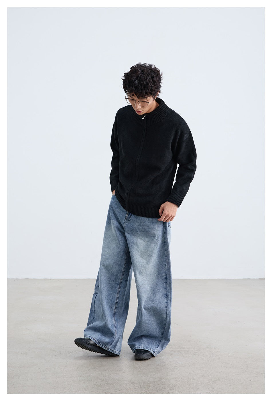Model wearing a black zip-front cardigan with a ribbed stand collar, styled with wide-leg blue jeans.