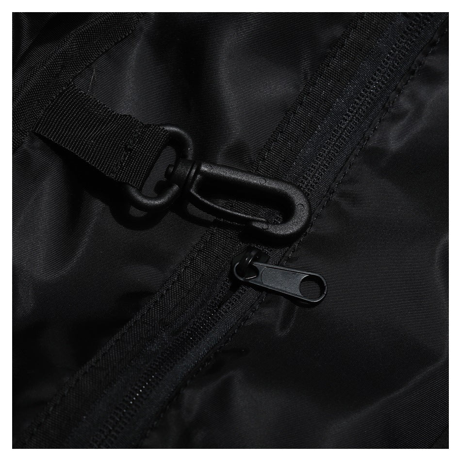 Close-up of a black bag's webbing strap, plastic hook clasp and zipper pull.