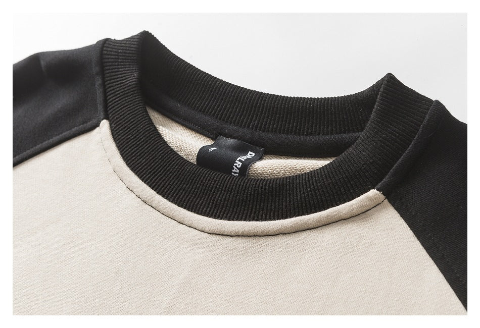 Close-up of the sweatshirt's black ribbed crew neck, cream neckline seam and inner label.
