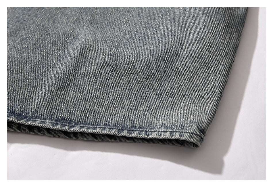 Close-up of the faded blue-gray denim jacket's stitched bottom hem.