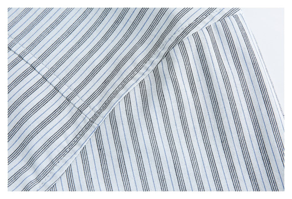 Close-up of white fabric with fine blue and dark stripes, showing a folded edge and seam.