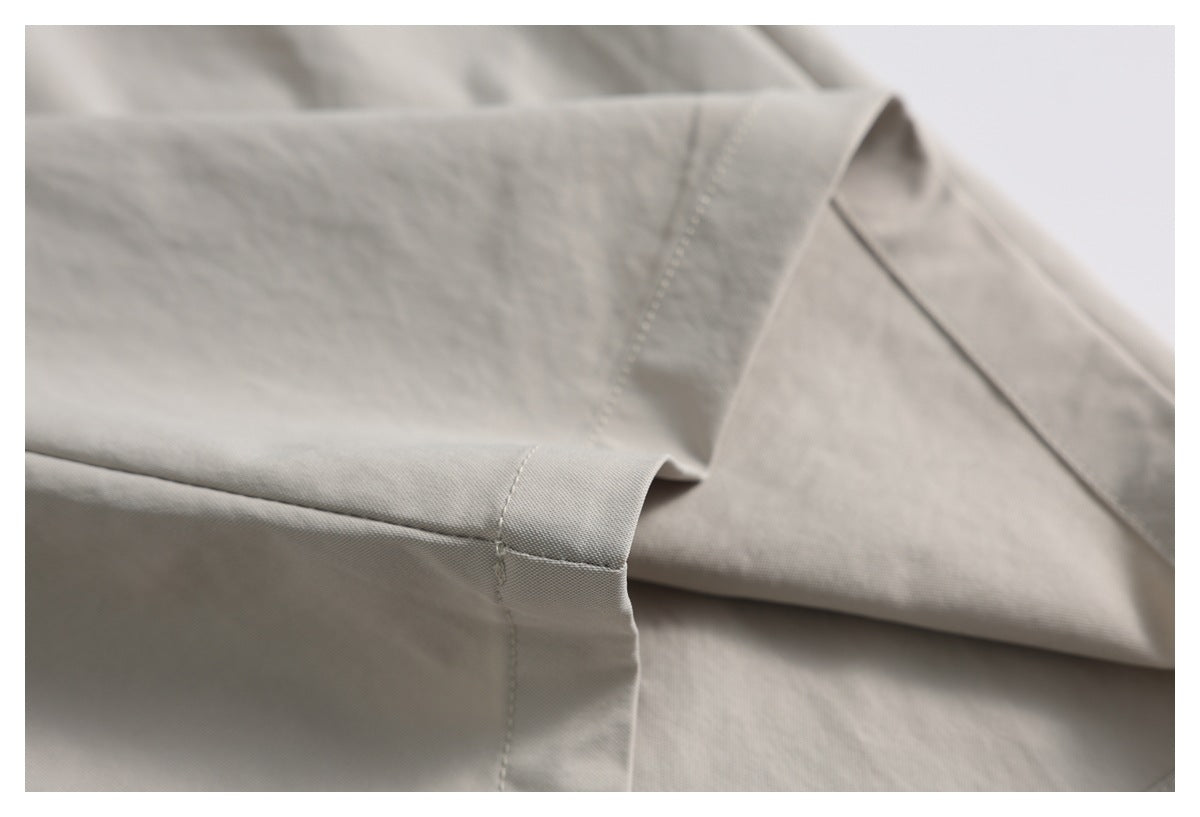 Close-up of light gray-beige fabric showing a folded edge and neat stitching.