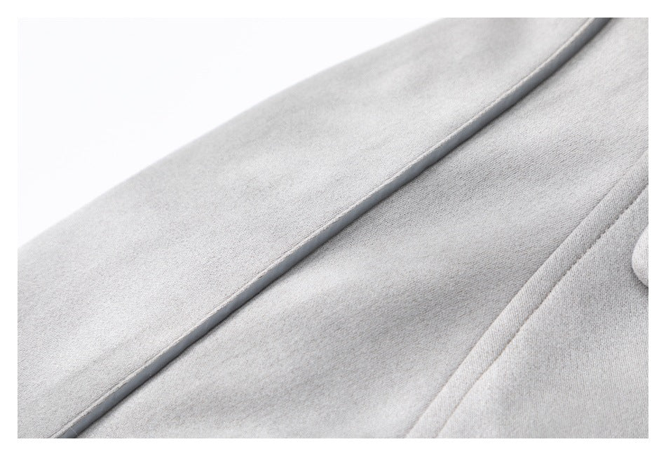 Close-up of light gray coat fabric with narrow dark piping along a seam.