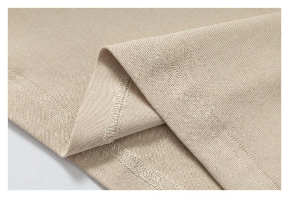 Close-up of beige garment seams, showing the hem stitching and overlocked inner seam.