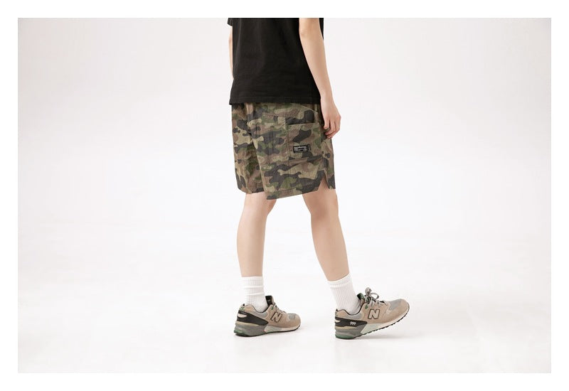 Rear three-quarter view of a model wearing camouflage shorts, showing the back pocket and hem.