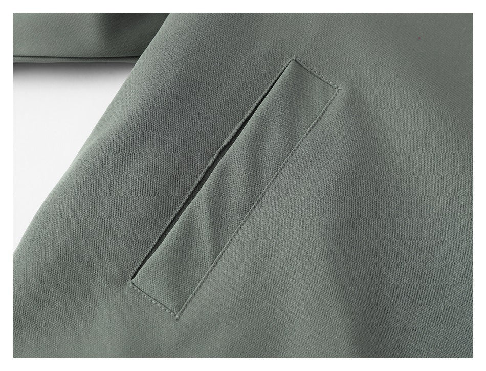 Close-up of a slanted welt pocket on the gray-green jacket.
