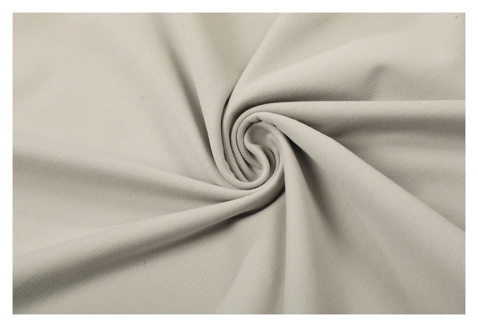 Close-up of light beige fabric arranged in a twist, showing its fine texture.