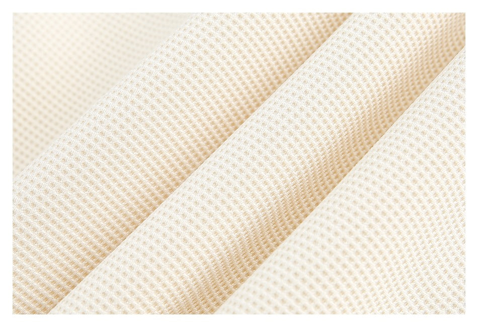 Macro view of ivory shirt fabric showing its raised, grid-like texture and folds.