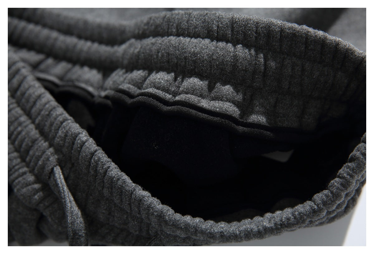 Close-up of a dark charcoal garment’s thick elastic waistband and black interior, with a matching drawstring.