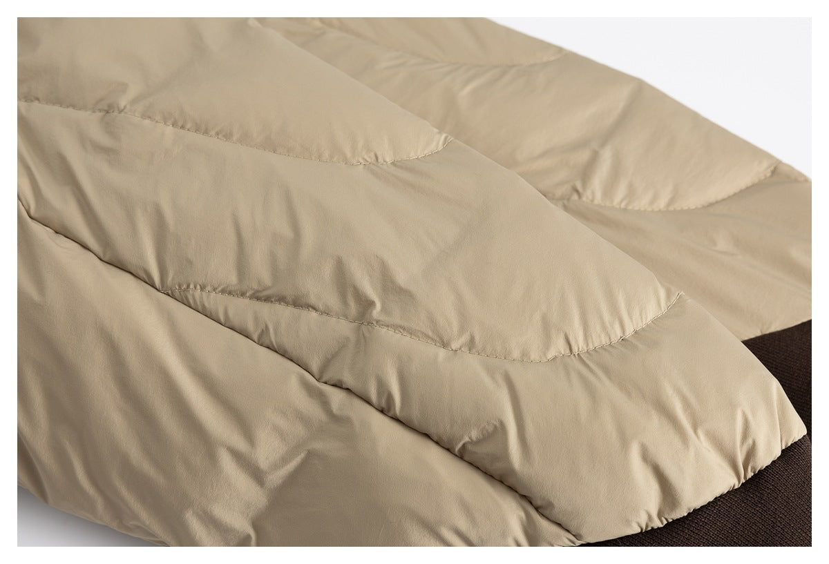 Close-up of a beige quilted comforter with broad stitched channels and a dark brown edge.