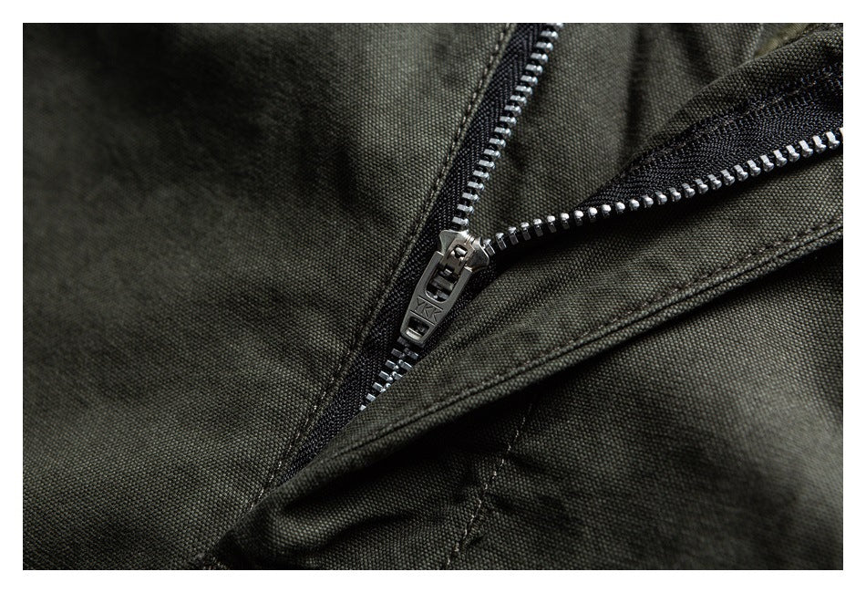 Close-up of a partially open metal zipper on dark olive fabric.