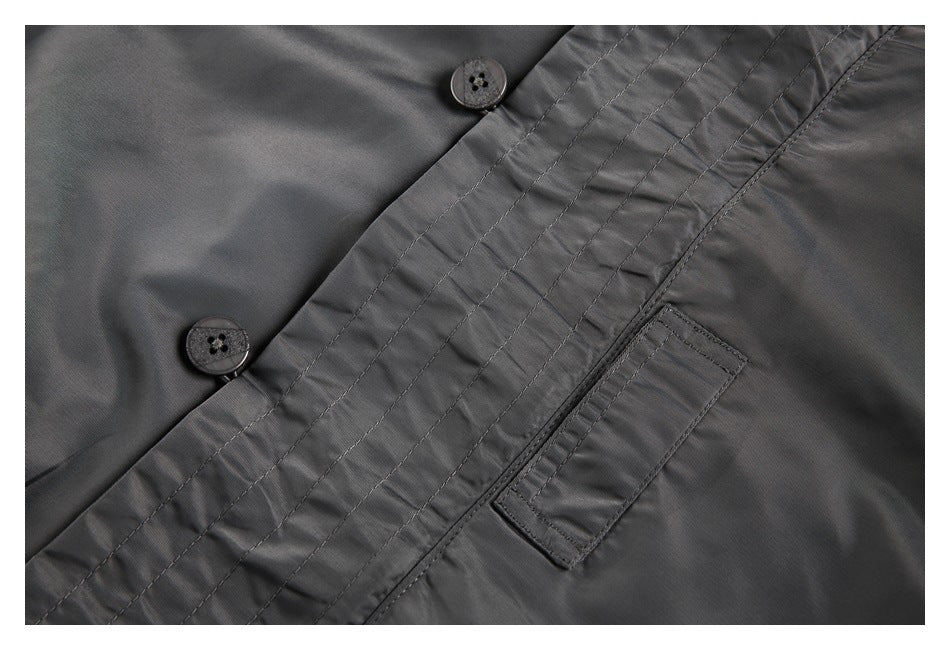 Close-up of a gray jacket's stitched button placket and small rectangular pocket.