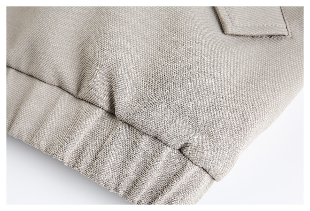 Close-up of the gray jacket's gathered hem and adjacent seam.