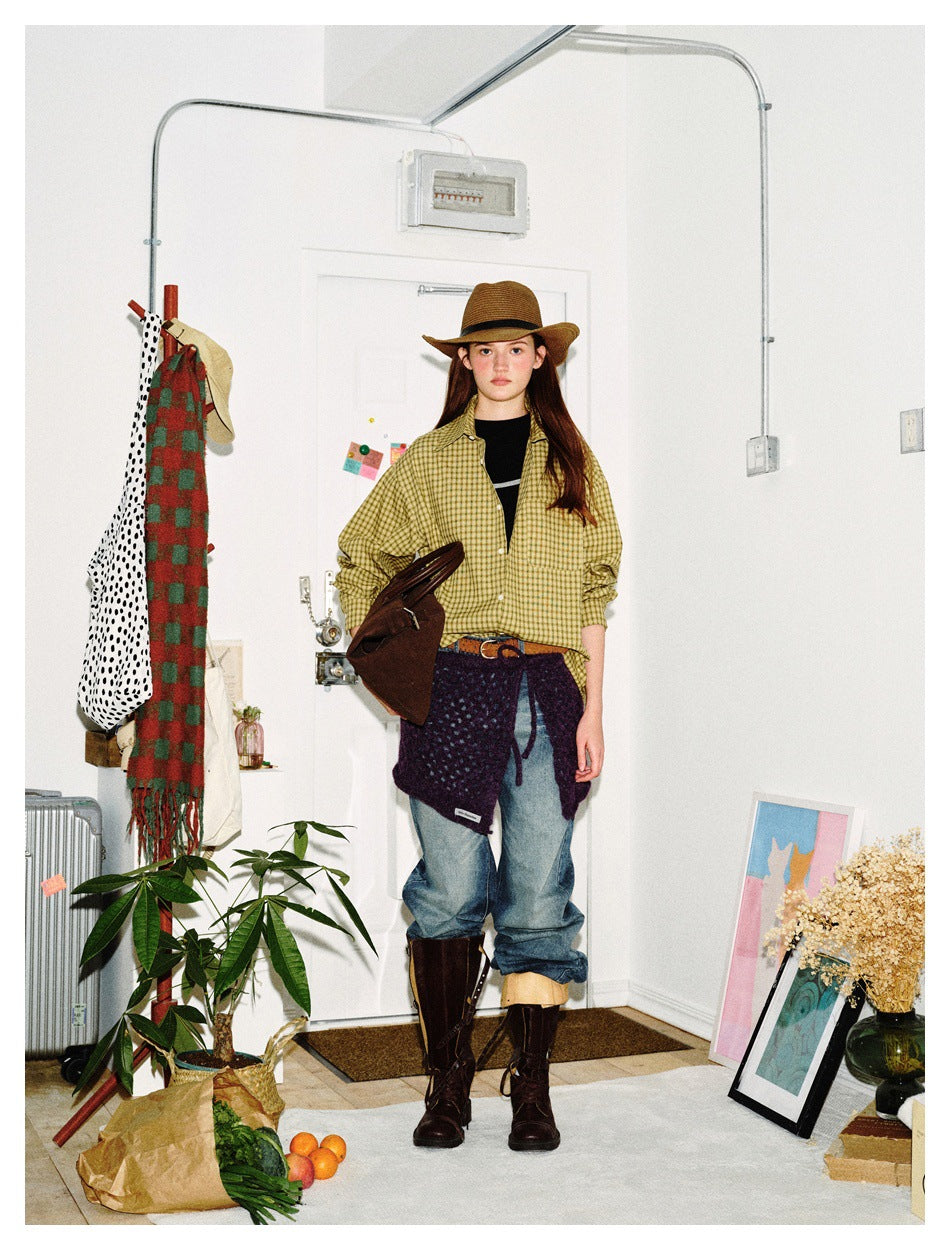 Full-length model wearing an olive-yellow plaid shirt, brown wide-brim hat, jeans, and tall brown boots.