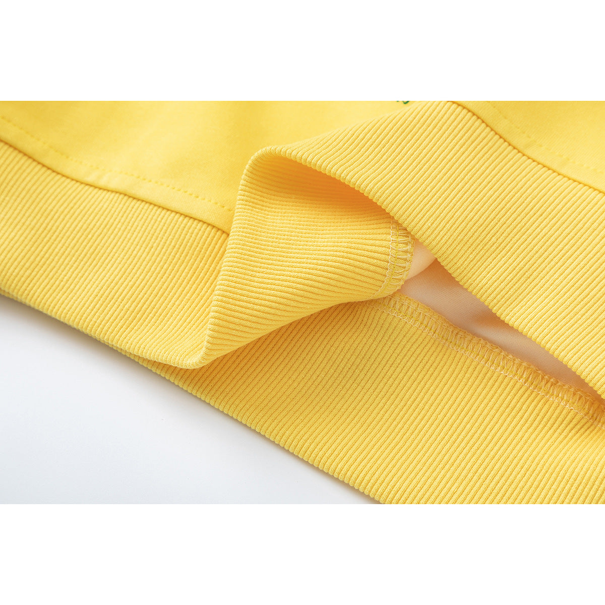 Close-up of a yellow sweatshirt's ribbed hem and stitched seam.