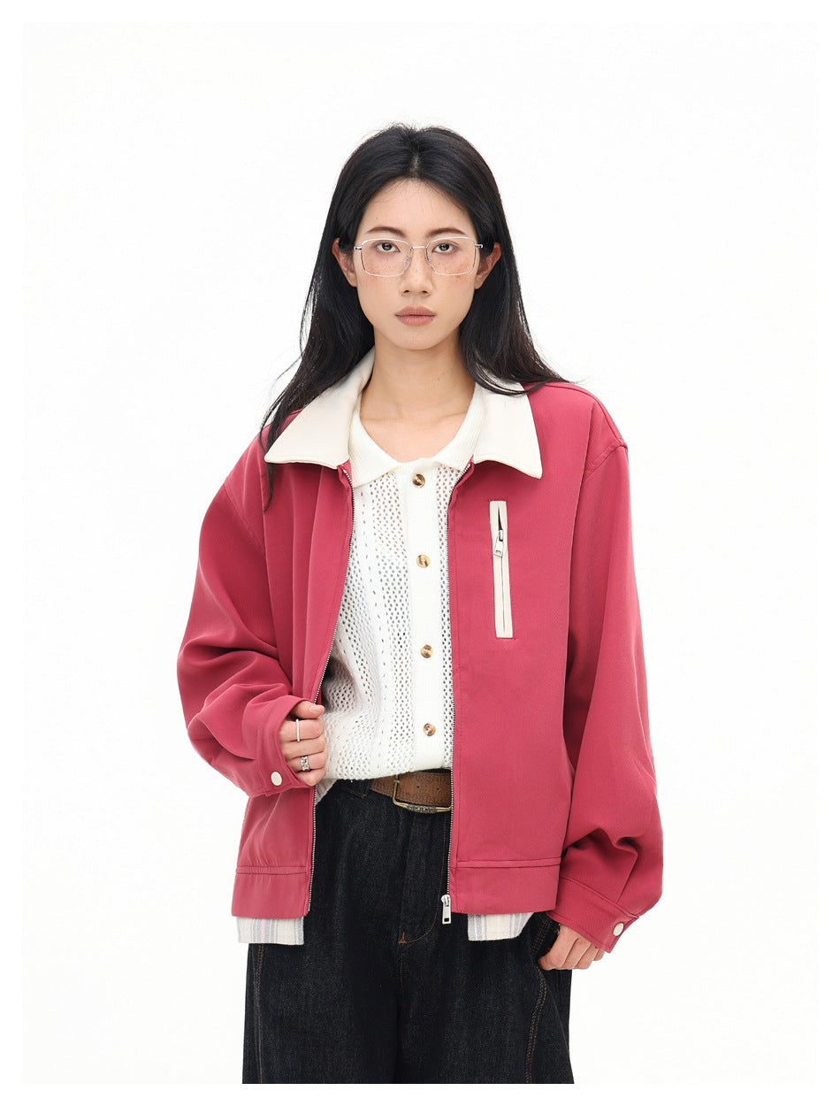 Closer view of a model wearing an open rose-pink jacket with a cream collar and vertical chest pocket zipper.