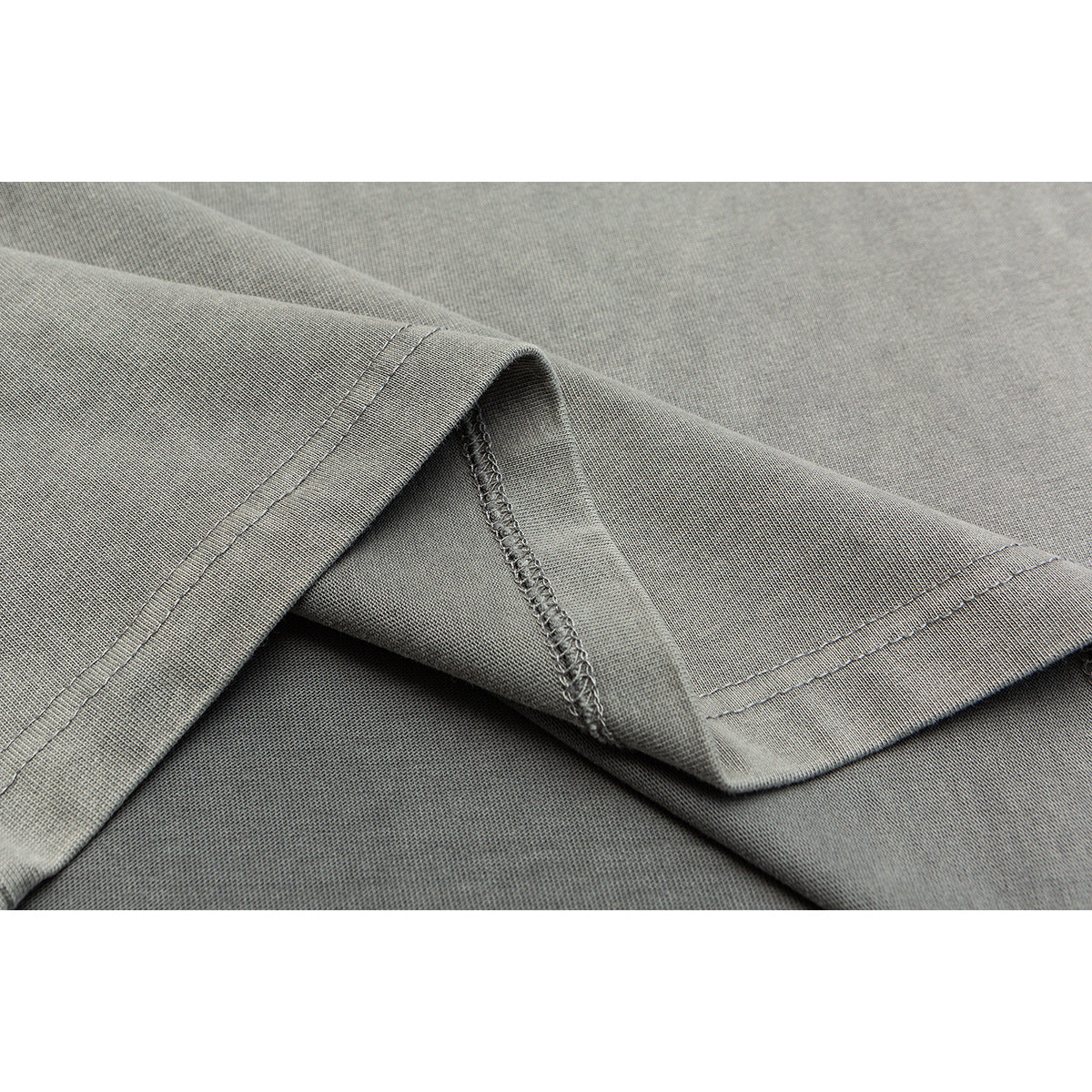 Close-up of the gray shirt’s folded hem, showing the double stitching and underside seam.