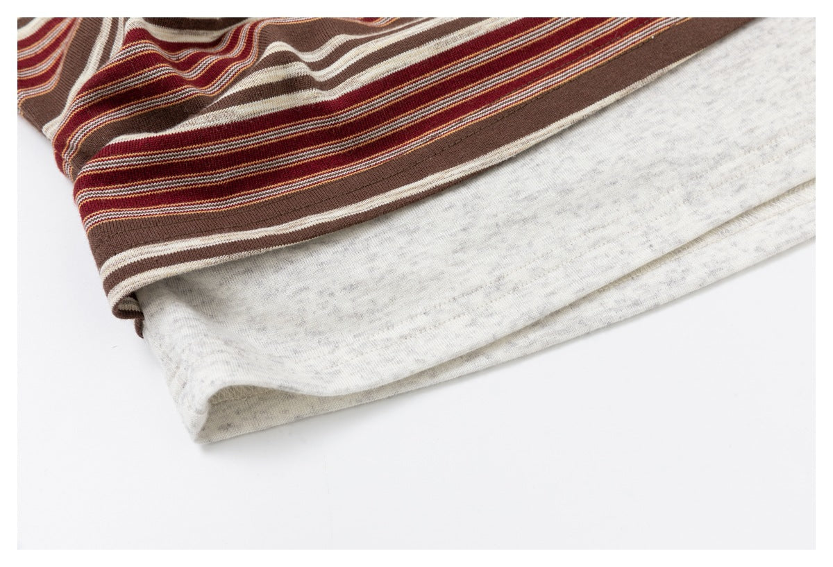 Close-up of a striped top's hem layered over a light gray section, with the folded edge visible.