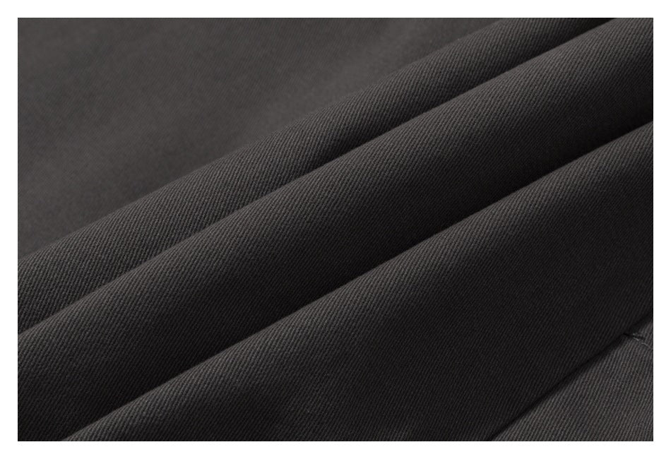Extreme close-up of dark charcoal fabric folded to show its fine diagonal texture.