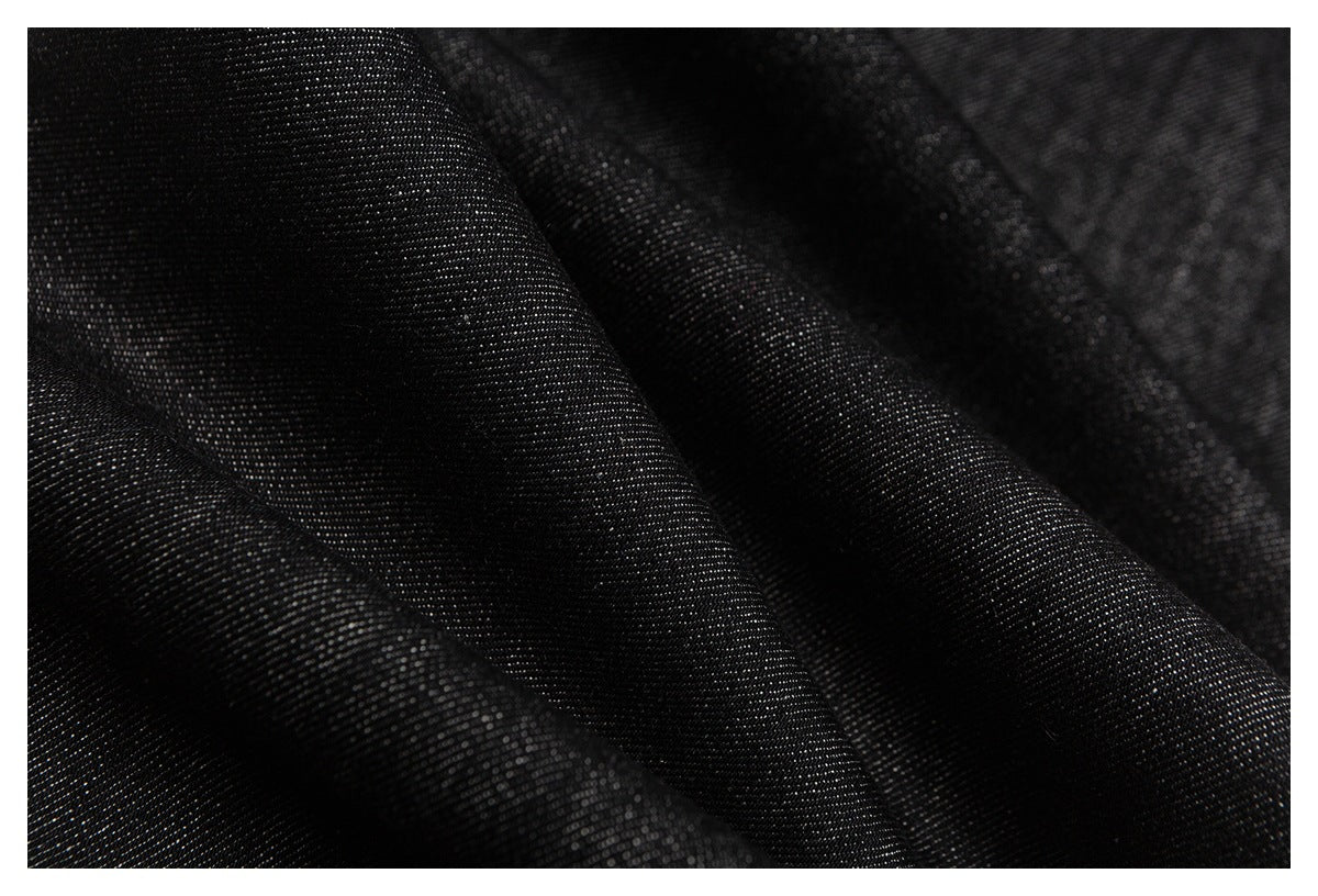 Macro view of black denim with a visible diagonal weave and soft folds.