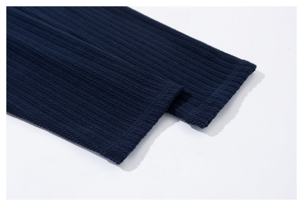 Close-up of the overlapping edge and hem of a navy ribbed garment on a white background.