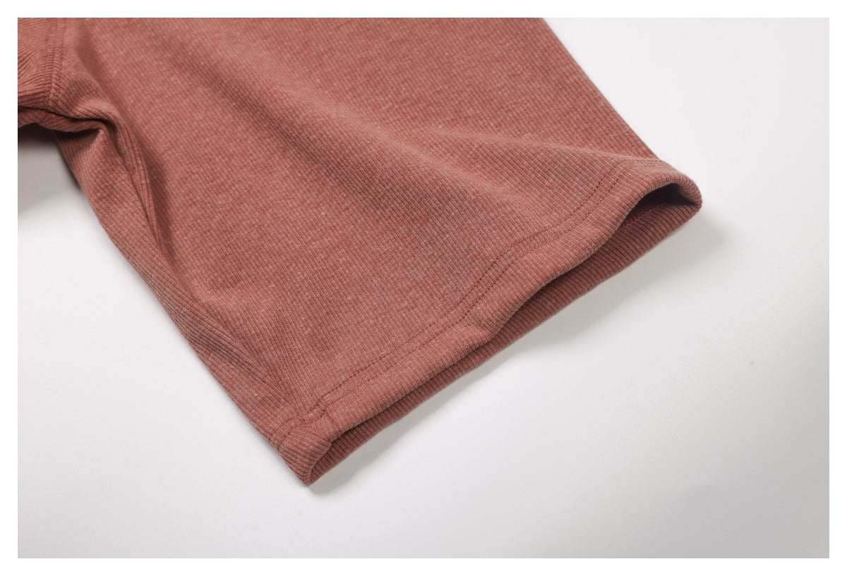 Close-up of a short sleeve opening and stitched hem on the dusty rose ribbed top.