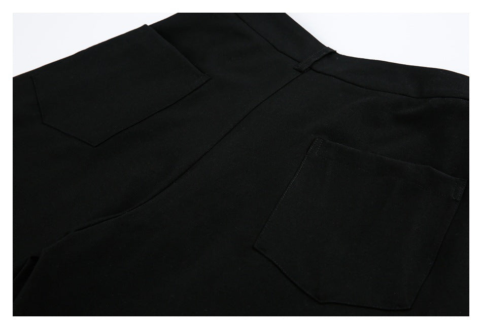 Close-up of black trousers showing two back patch pockets and seam stitching.