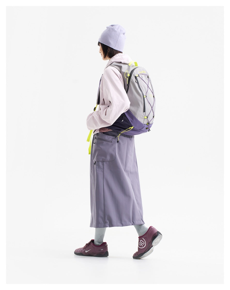 A person wearing a gray and purple backpack with neon yellow details, shown from the side and back.