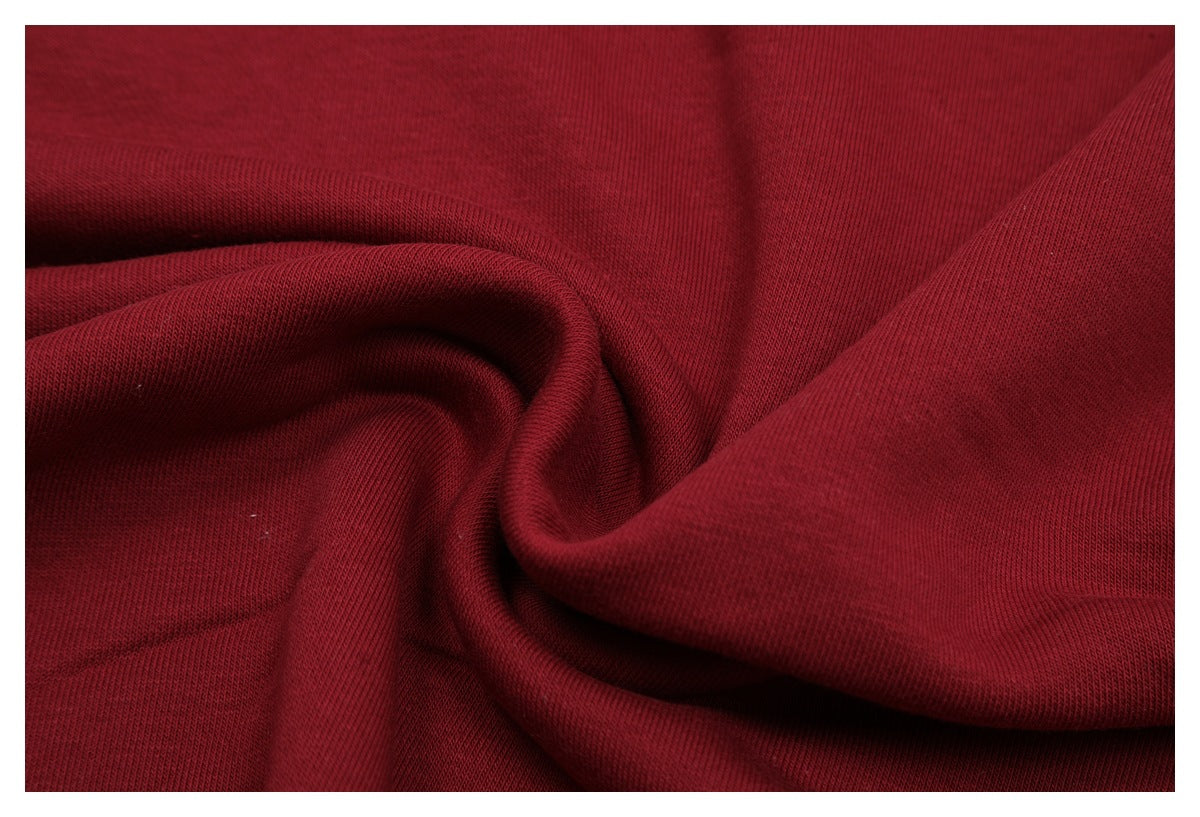 Close-up of burgundy sweatshirt fabric draped in folds, showing its surface texture.