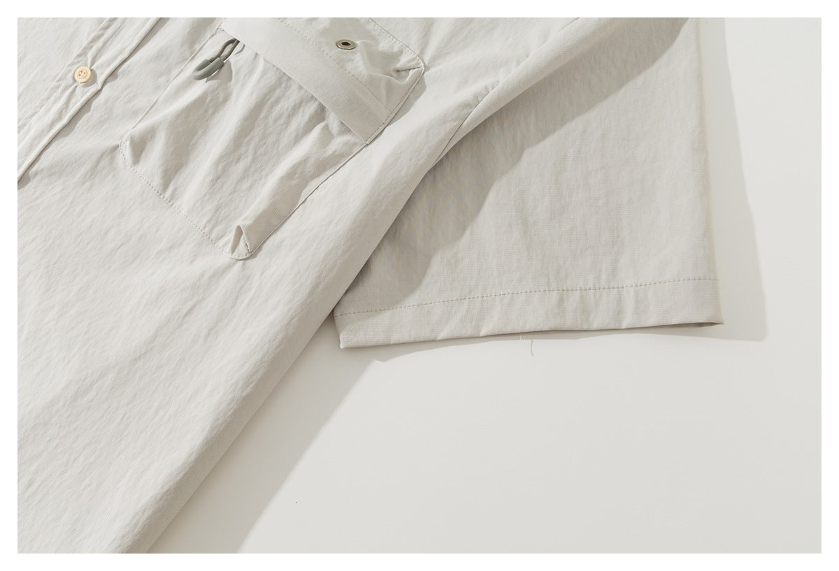 Close-up of the off-white shirt's short sleeve and stitched hem beside part of its pocket.