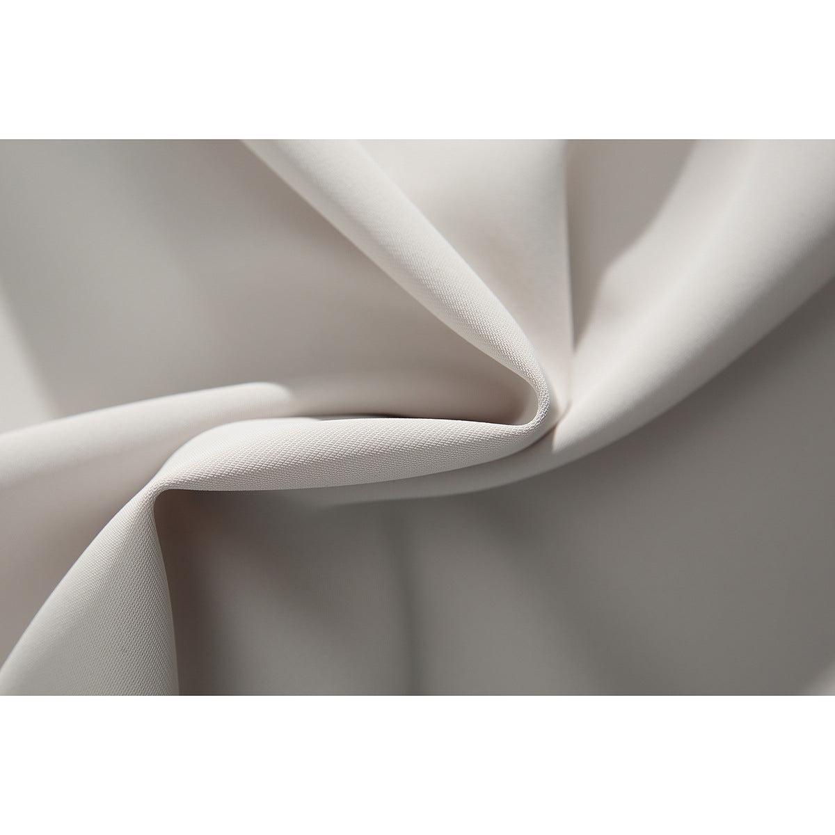 Close-up showing the fine woven texture and folds of off-white fabric.