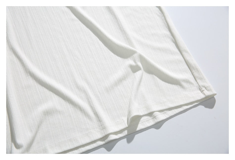 Close-up of the white shirt's ribbed lower body and stitched bottom hem.