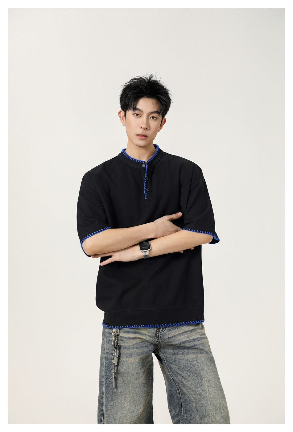 Model wearing a black short-sleeve shirt with bright blue contrast stitching at the collar, cuffs and hem.