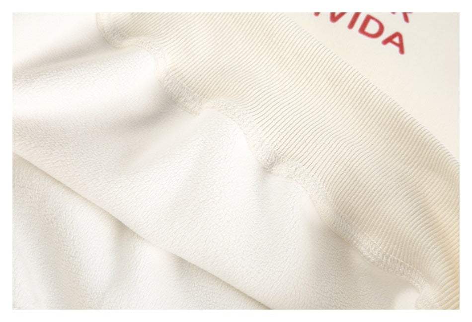 Close-up of cream sweatshirt fleece and ribbed fabric, with partial red lettering visible at the edge.