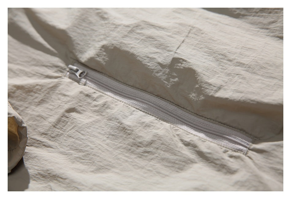 Close-up of a pale zipper across the crinkled beige jacket fabric.