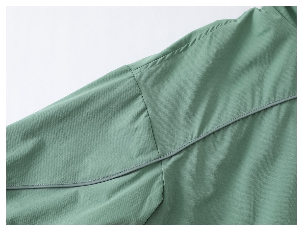 Close-up of a sage green jacket sleeve and shoulder seam with narrow contrast piping.