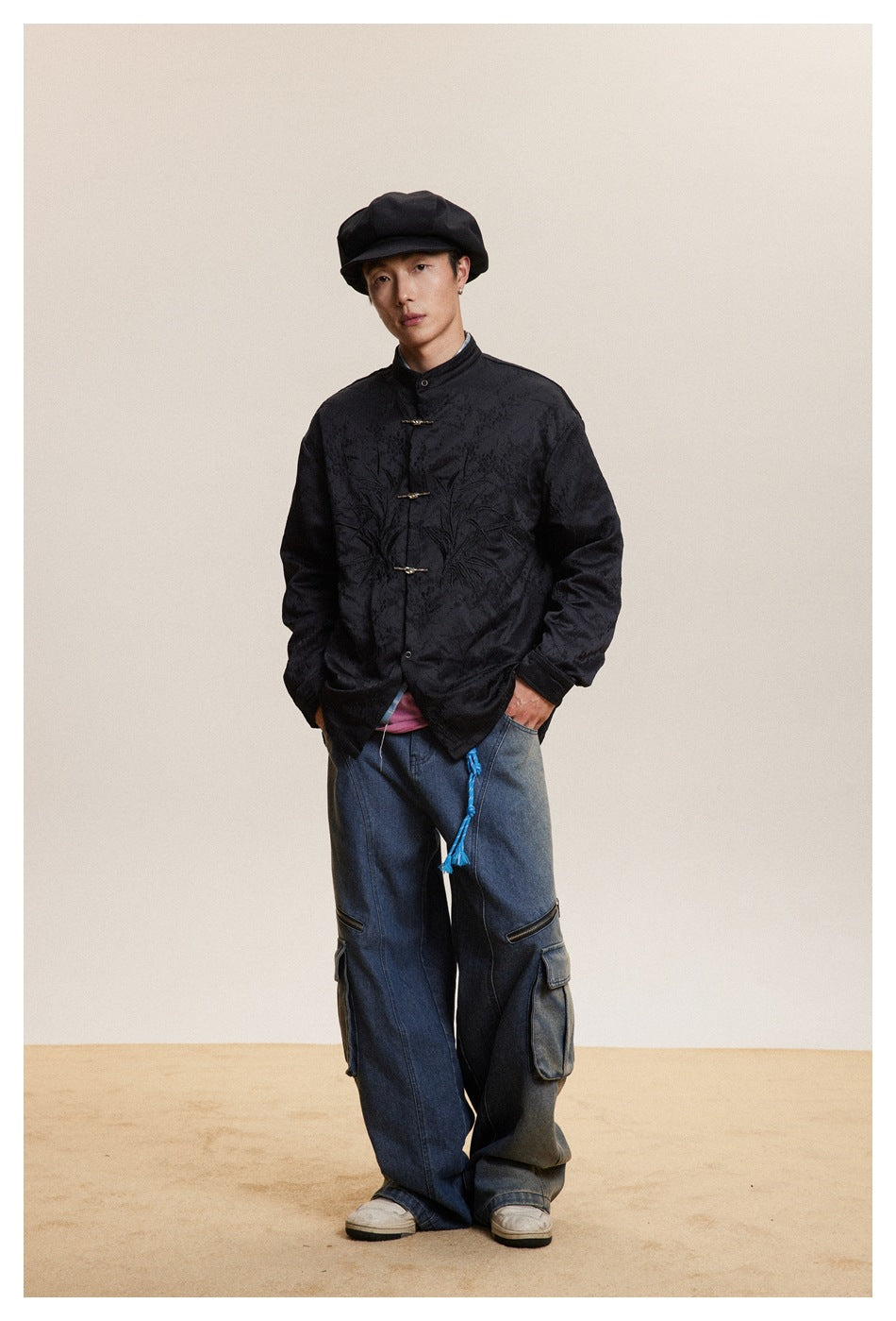 Full-length model wearing a black tonal embroidered jacket with frog closures and loose blue cargo jeans.