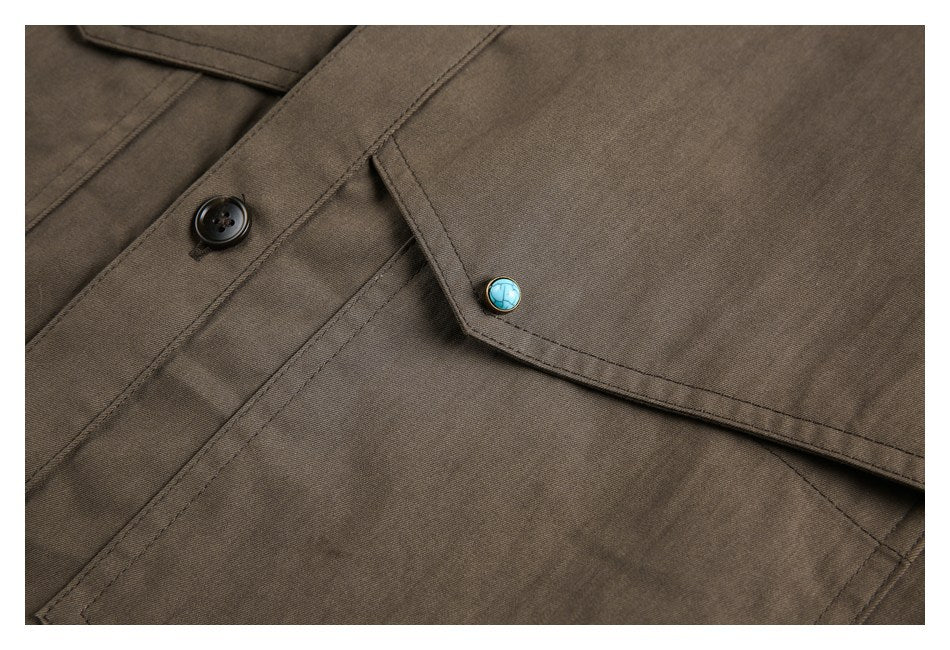 Close-up of a brown shirt pocket flap with a turquoise button and a black front button.
