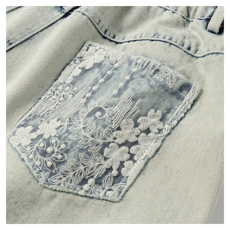 Close-up of a faded denim back pocket covered in white floral embroidery.