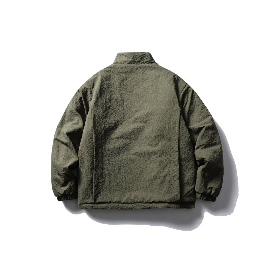 Back view of an olive green jacket laid flat, with a stand collar, long sleeves, and elasticated cuffs.