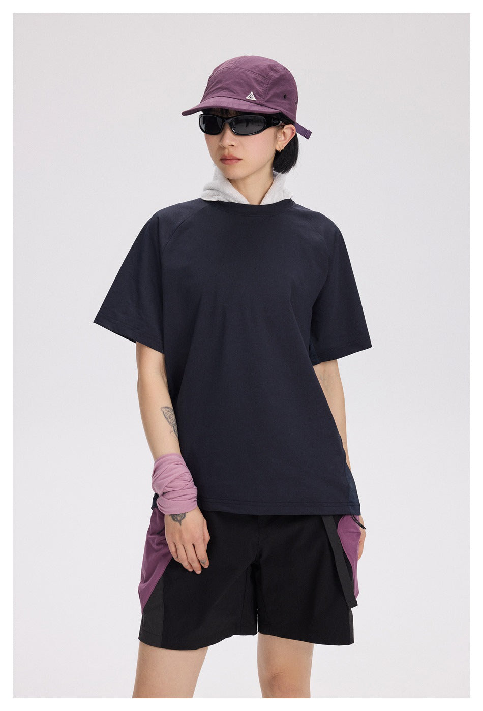 Front view of a model wearing a plain dark navy short-sleeve T-shirt and black shorts with purple side panels.