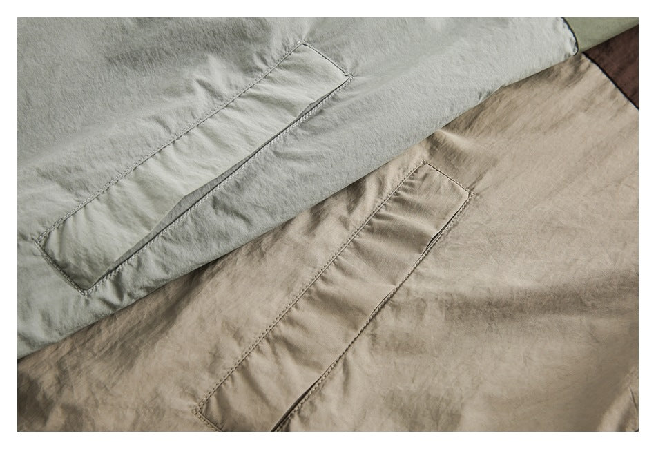 Close-up of long slanted welt pockets on sage green and taupe jackets.