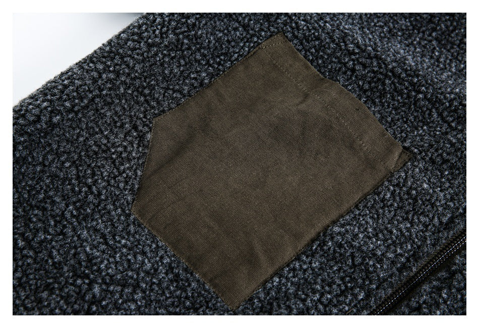 Close-up of a dark charcoal textured garment with a large brown patch pocket and part of a zipper.