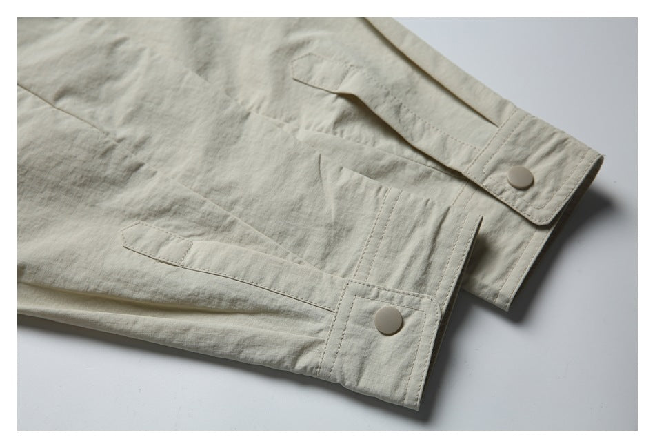 Close-up of the light beige jacket's adjustable cuff tabs with snap buttons and stitched seams.
